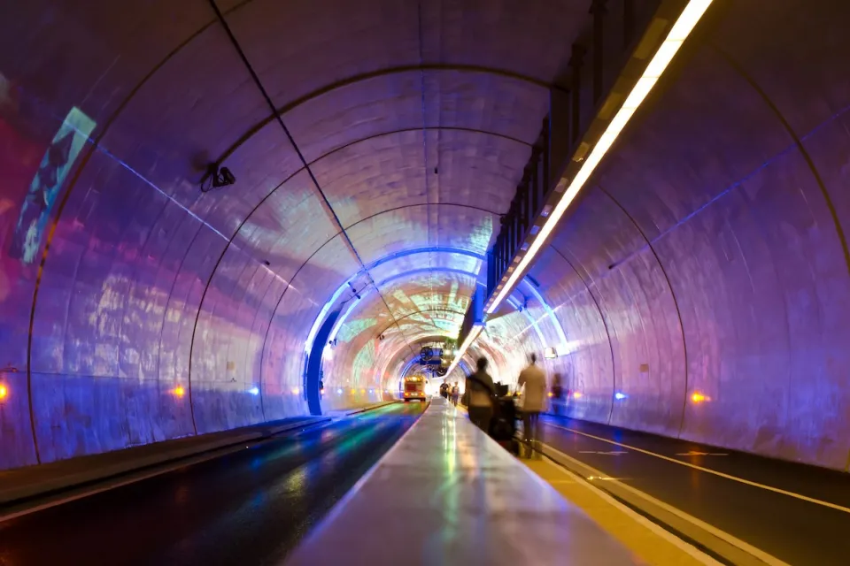 Tunnel for pedestrians, bikes, and buses in Lyon, France lit up with purple lights.
